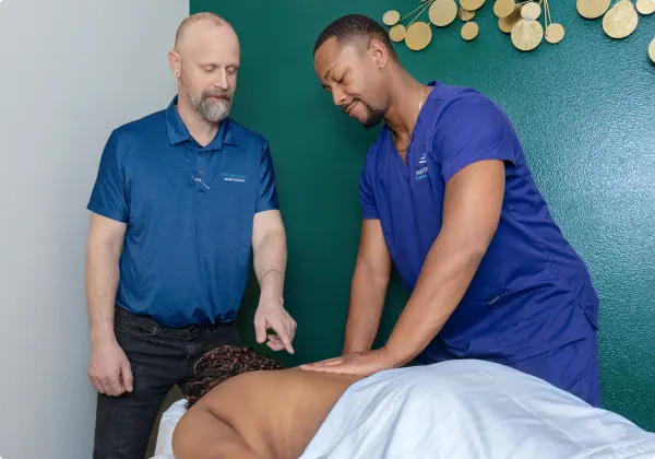 Massage therapy classes in Las Vegas at Northwest Career College with instructor guiding a student during hands-on training