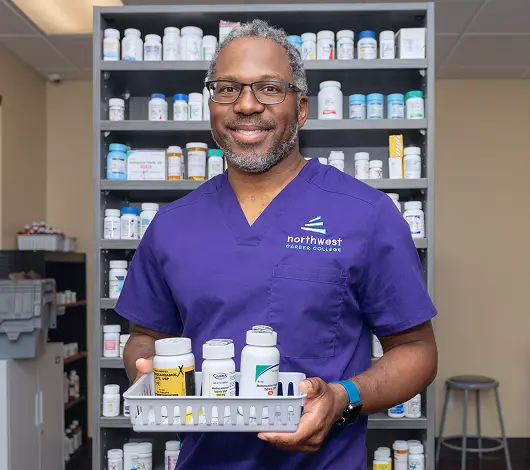 Pharmacy Tech programs student in Las Vegas at Northwest Career College holding prescription tray in pharmacy lab