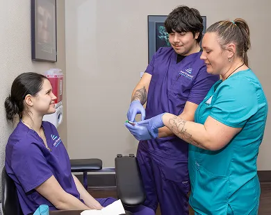 Phlebotomy certification training in Las Vegas at Northwest Career College with instructor guiding students during practice