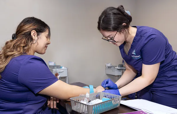 Phlebotomy classes in Las Vegas at Northwest Career College with students practicing blood draw techniques
